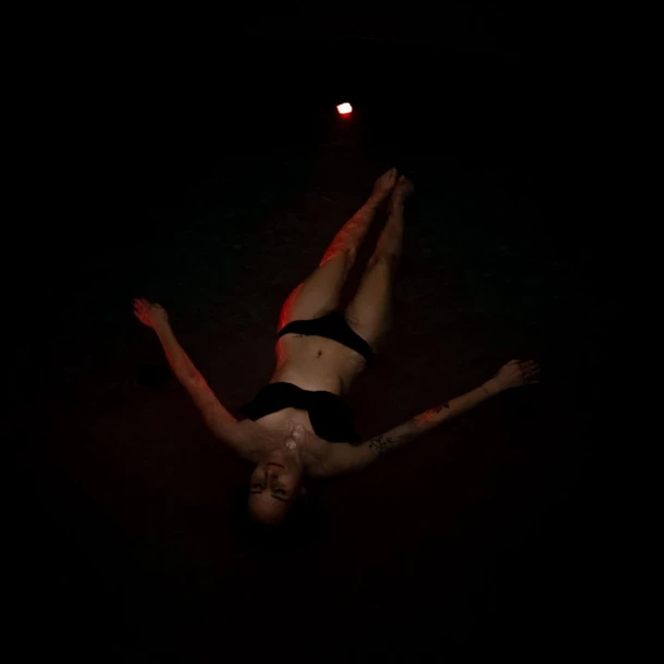 Eine Person liegt in dunklem Wasser und entspannt sich, beleuchtet von schwachem Licht.