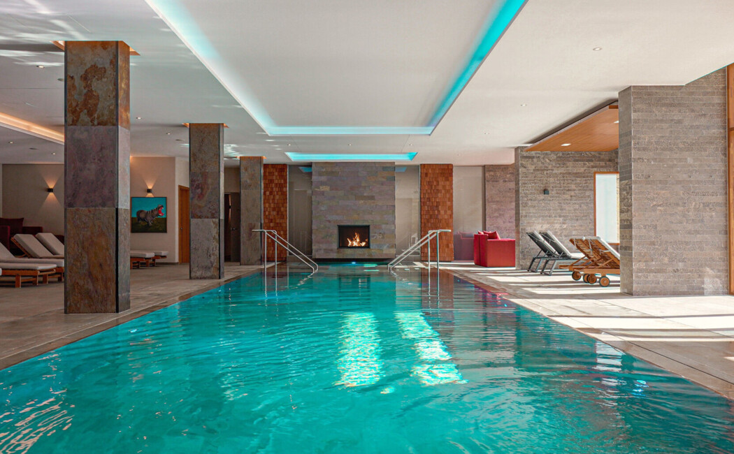 Indoor-Pool mit Kaminlounge im Panoramahallenbad des Wellnesshotel Klosterhof im Berchtesgadener Land.