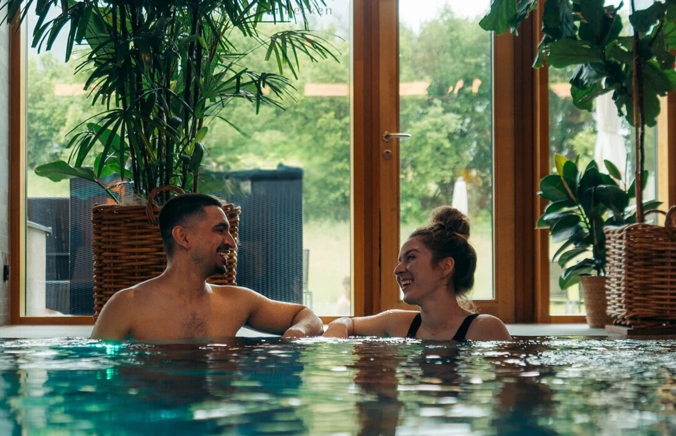 Ein Paar genießt Zeit im Pool des Wellnesshotels Klosterhof, umgeben von Pflanzen und natürlichem Licht.
