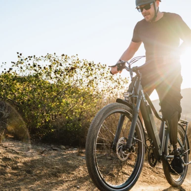 A person rides an electric mountain bike on a sunny trail, showcasing adventure and outdoor activity.
