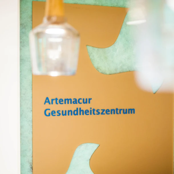 Schild des Artemacur Gesundheitszentrums, umgeben von sanften Farben, im Hotel Klosterhof, einem Wellnesshotel in Bayerisch Gmain.