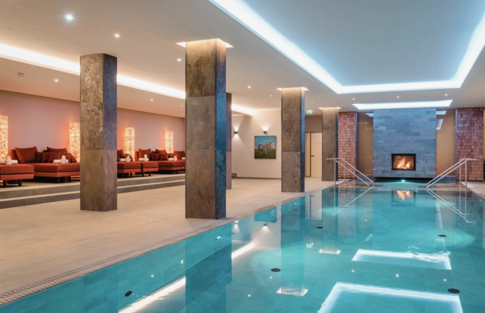 Indoor-Hallenbad mit Kaminlounge im Alpine Hideaway & Spa Hotel Klosterhof in Bayerisch Gmain.