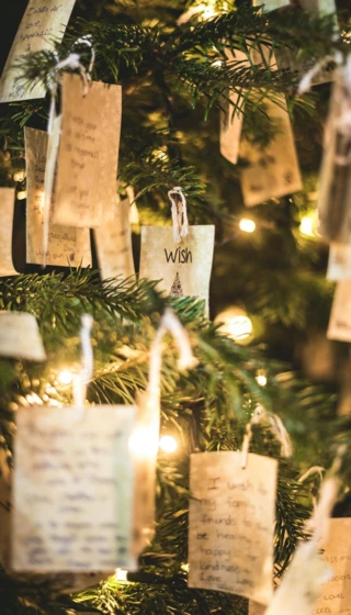 Wünsche auf Papierzetteln hängen an einem beleuchteten Weihnachtsbaum im Hotel Klosterhof.
