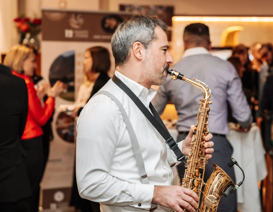 Ein Saxophonist spielt auf einer Veranstaltung im Hotel Klosterhof, umgeben von Gästen in festlicher Stimmung.