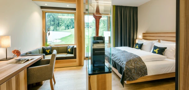 Helles Zimmer im Hotel Klosterhof mit modernem Design, gemütlicher Sitzecke und Blick auf die umliegende Natur in Bayerisch Gmain.