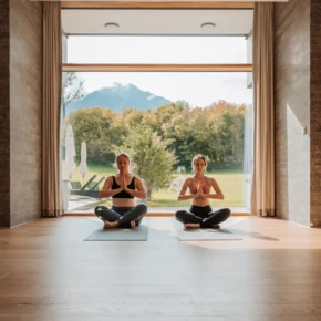 Zwei Frauen meditieren auf Yogamatten im Hotel Klosterhof, umgeben von der Natur und den Alpen in Bayerisch Gmain.