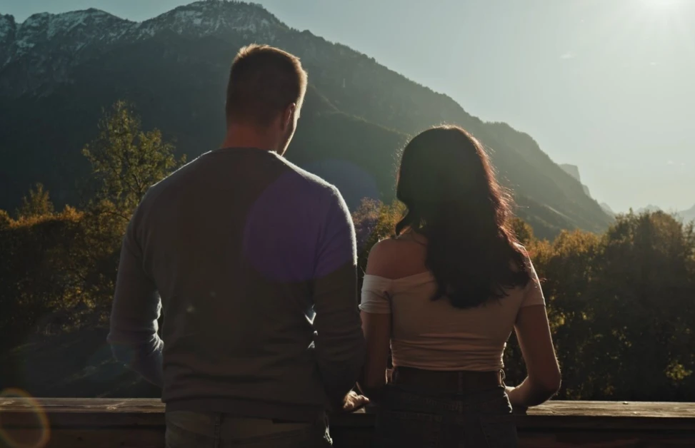 Ein Paar steht auf dem Balkon ihres Hotelzimmers und genießt den Ausblick auf die Bergwelt im Berchtesgadener Land.
