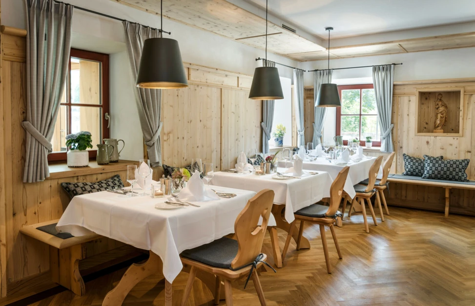 Gemütlicher Speisesaal im Hotel Klosterhof mit Holzdekor, eleganten Tischen und warmem Licht in Bayerisch Gmain.