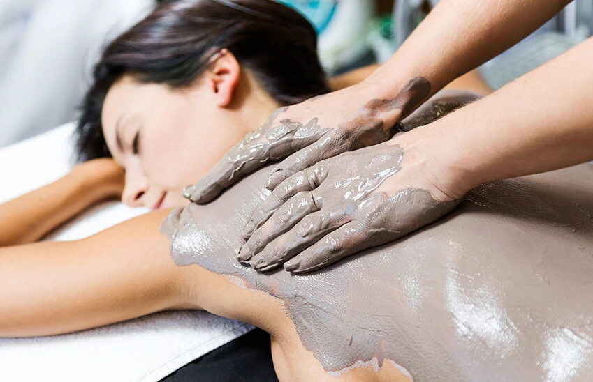 A person receiving a relaxing mud body treatment at a spa.