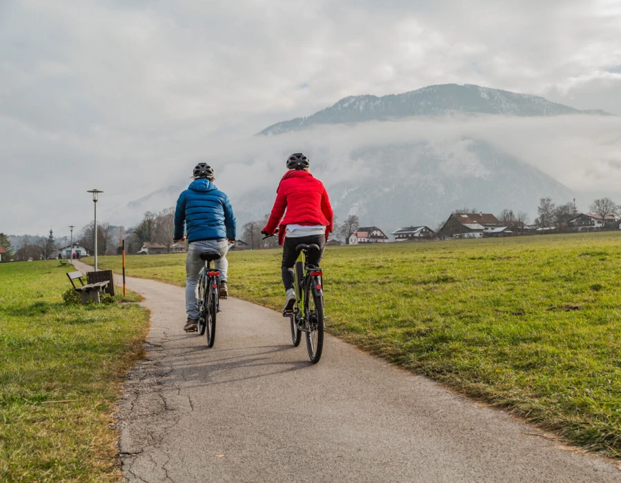 Zwei Radfahrer auf einem Weg in Bayerisch Gmain mit Blick auf die Alpen, nahe dem Wellnesshotel Klosterhof, einem Alpine Hideaway & Spa in Bayern.