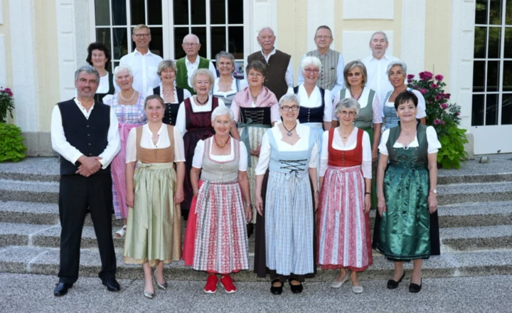 Eine Gruppe von Menschen in traditioneller Tracht steht vor einem Gebäude.