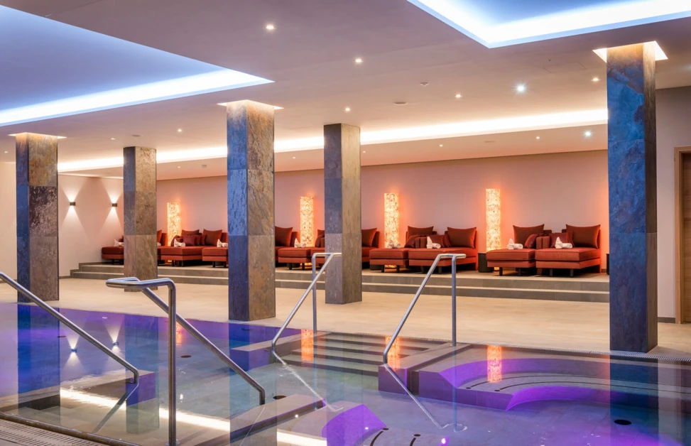 Elegante Spa-Atmosphäre mit einem Poolbereich und gemütlichen Sitzgelegenheiten, ideal für Entspannung und Wellness.