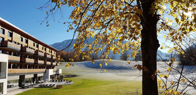 Herbstliche Aussicht auf das Hotel Klosterhof in Bayerisch Gmain mit bunten Bl&auml;ttern, Bergkulisse und gr&uuml;nem Rasen. Ideal f&uuml;r Wellness und Entspannung.