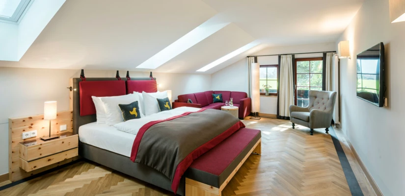 Helles, modernes Zimmer im Hotel Klosterhof mit zwei Betten, gemütlicher Sitzecke und Blick auf die Alpen. Ideal für Wellness und Entspannung.
