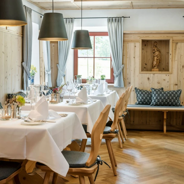 Helles, einladendes Restaurant mit Holzelementen, eleganten Tischgedecken und gemütlicher Atmosphäre.