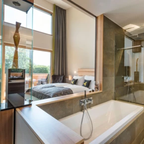 Modernes Badezimmer mit Badewanne und Dusche, Blick auf das Schlafzimmer im Hotel Klosterhof, Bayerisch Gmain. Ideal für Entspannung und Wellness.