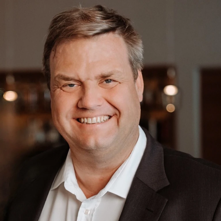 Smiling man in a suit, indoors.