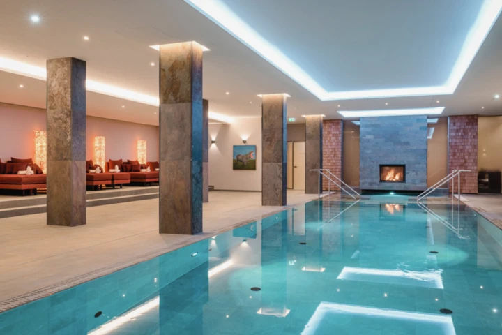 Indoor-Hallenbad mit Kaminlounge im Alpine Hideaway & Spa Hotel Klosterhof in Bayerisch Gmain.