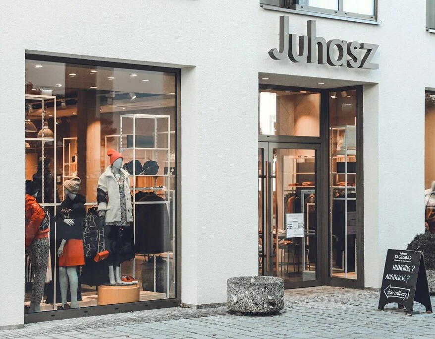 Schaufenster des Juhasz-Geschäfts mit modischen Outfits und einem einladenden Eingangsbereich.