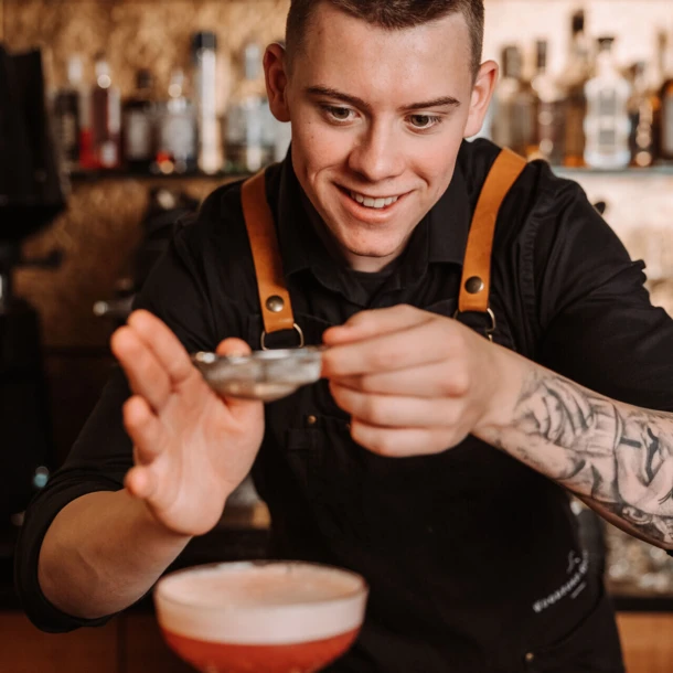 Ein Barkeeper bereitet einen Cocktail in der Hotelbar des Wellnesshotels Klosterhof in Bayerisch Gmain zu.