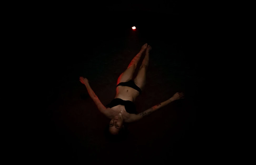 A person floating in a dimly lit water pool, creating a serene atmosphere at Wellnesshotel Klosterhof in Bayern.
