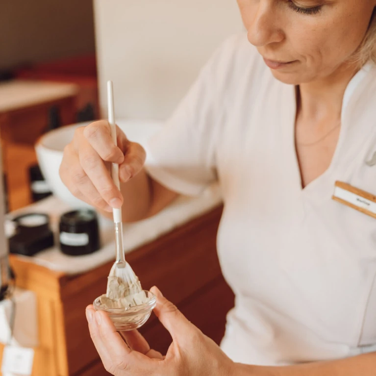 Spa-Mitarbeiterin bei der Vorbereitung für eine Maske mit Naturkosmetik.
