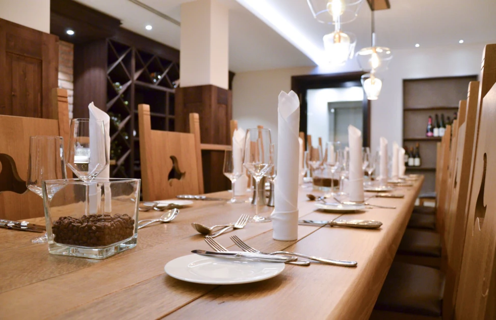 Ein eleganter Tisch im Klosterhof, liebevoll gedeckt mit Gläsern, Besteck und Servietten, umgeben von Holzdetails.