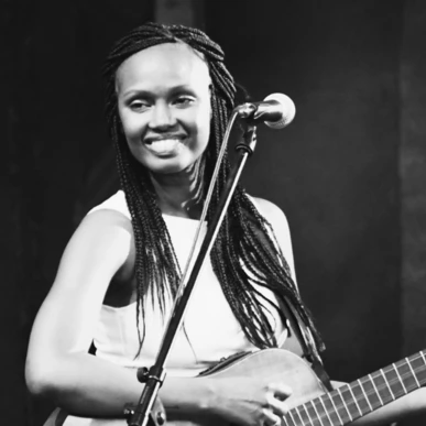 Eine Musikerin spielt Gitarre und singt auf der Bühne.