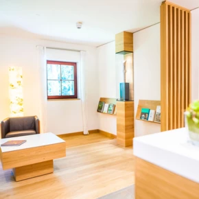 Heller Empfangsbereich im Hotel Klosterhof mit modernem Design, Pflanzen und Büchern. Gemütliche Atmosphäre in Bayerisch Gmain.
