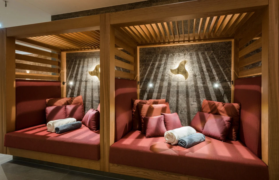 Gemütliche Kabinen mit roten Polstern und Handtüchern in einem modernen Wellnessbereich, ideal zum Entspannen und Erholen.