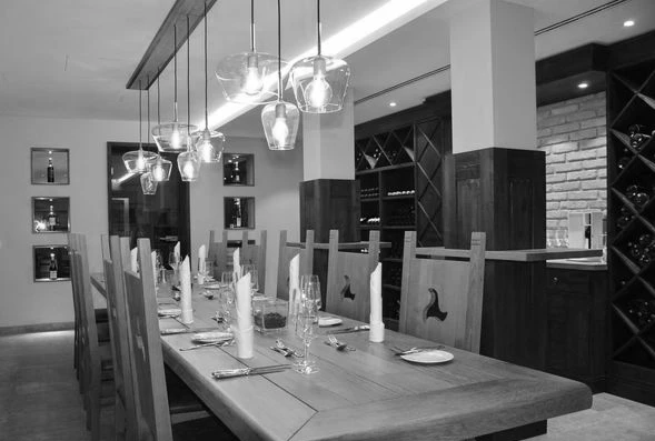 Ein eleganter Speisesaal mit rustikalem Holztisch, modernen Lampen und stilvollem Geschirr, ideal f&uuml;r gesellige Anl&auml;sse.