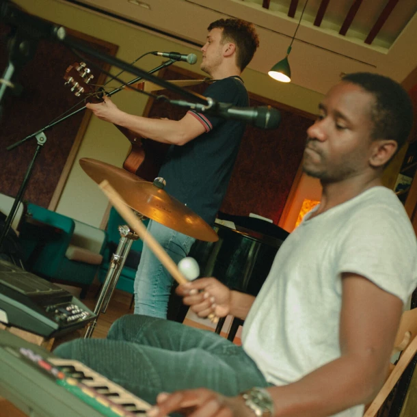 Ein Musiker singt und spielt Gitarre, während ein anderer am Keyboard mit einem Drumstick spielt. Gemütliche Atmosphäre im Hotel Klosterhof.