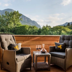 Gemütliche Sitzecke auf dem Balkon mit Blick auf Berge und Natur, perfekt für entspannte Momente mit Wein.