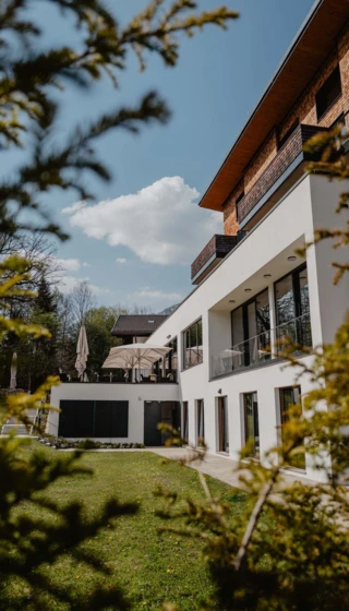 Moderne Architektur des Hotel Klosterhof in Bayerisch Gmain, umgeben von Natur, mit Terrassen und Sonnenschirmen.