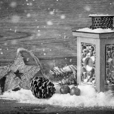 Eine festliche Laterne auf einem holzigen Tisch, umgeben von Tannenzapfen, Sternen und winterlicher Dekoration im Schnee.
