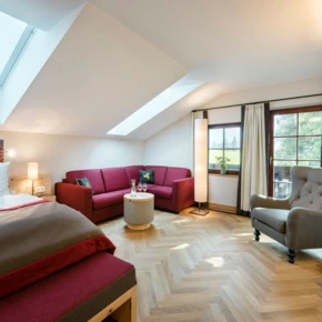 Helles, modernes Zimmer im Hotel Klosterhof mit Dachfenstern, gem&uuml;tlicher Sitzecke und Blick auf die Natur in Bayerisch Gmain.