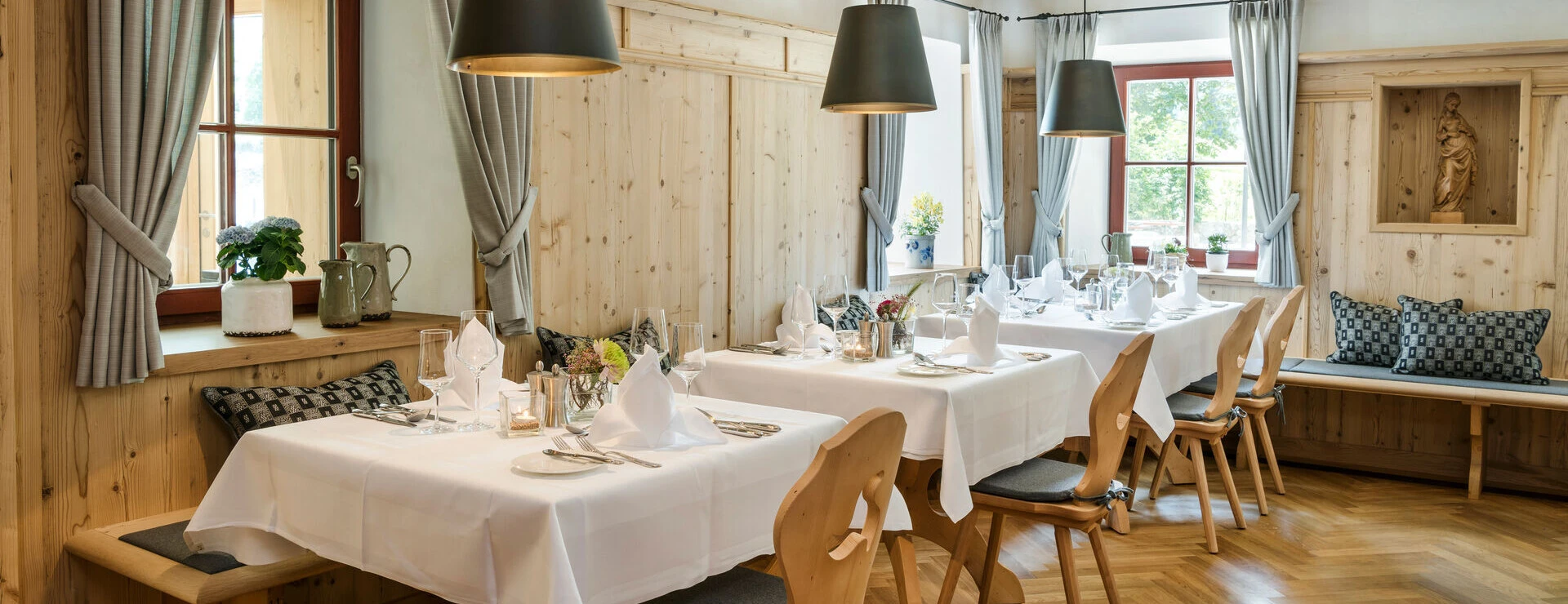 Gemütlicher Speisesaal im Hotel Klosterhof mit Holzdekor, eleganten Tischen und warmem Licht in Bayerisch Gmain.