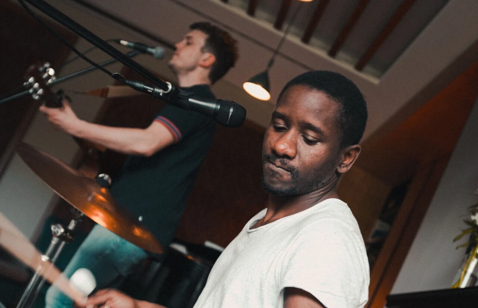 Musicians performing with keyboard and guitar in a cozy indoor setting.