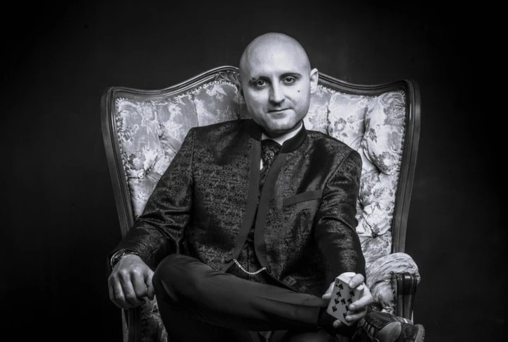 Ein Mann in einem Sessel hält eine Spielkarte in der Hand, schwarz-weiß Fotografie.