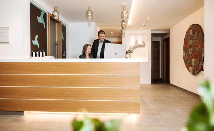 Moderne Rezeption mit freundlichem Personal in einem stilvollen Foyer, das einladend gestaltet ist.