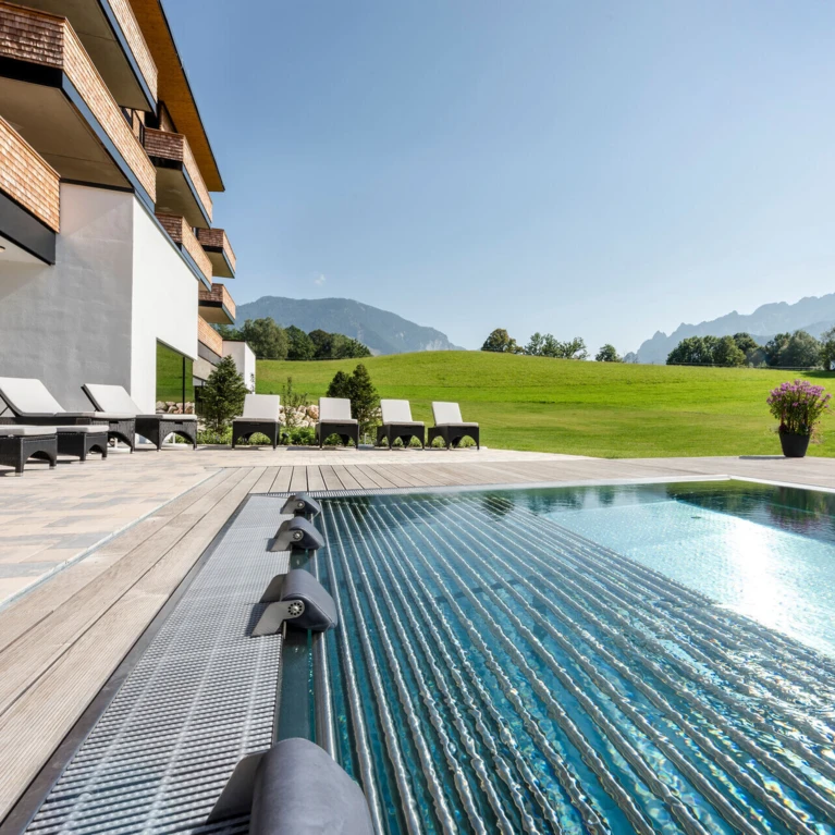 Luxuriöser Poolbereich des Hotel Klosterhof mit Blick auf die Alpen und gepflegte Rasenflächen in Bayerisch Gmain.