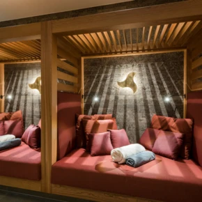 Gemütliche Kabinen mit roten Polstern und Handtüchern in einem modernen Wellnessbereich, ideal zum Entspannen und Erholen.