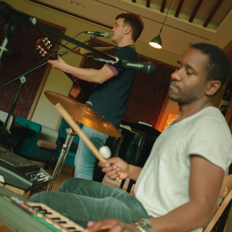 Ein Musiker singt und spielt Gitarre, während ein anderer am Keyboard mit einem Drumstick spielt. Gemütliche Atmosphäre im Hotel Klosterhof.