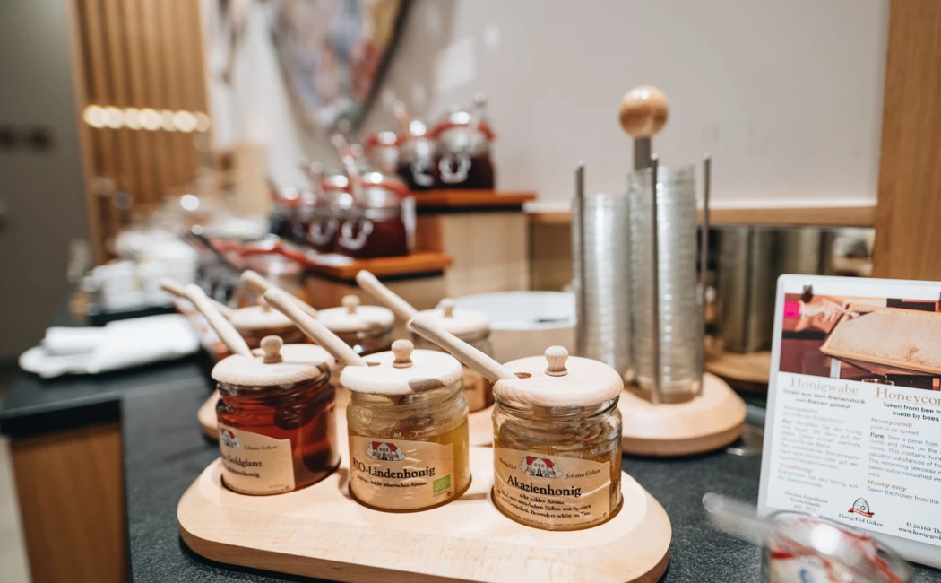 Ein stilvolles Buffet mit Honiggläsern und Holzlöffeln im Hotel Klosterhof, ideal für ein genussvolles Frühstück.