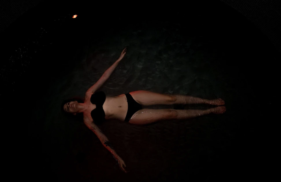 Eine Person schwimmt entspannt im Wasser, umgeben von sanften Lichtreflexionen.