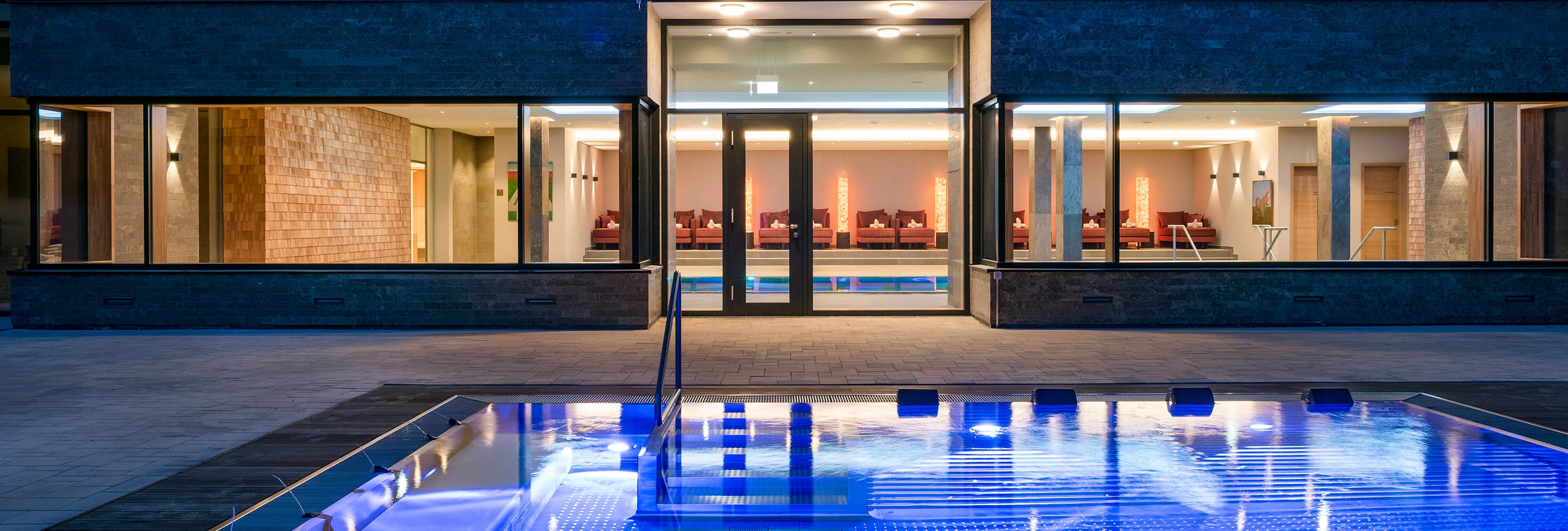 Ein beleuchteter Pool vor dem Hotel Klosterhof, mit Blick auf die stilvolle Innenausstattung und entspannende Atmosphäre.