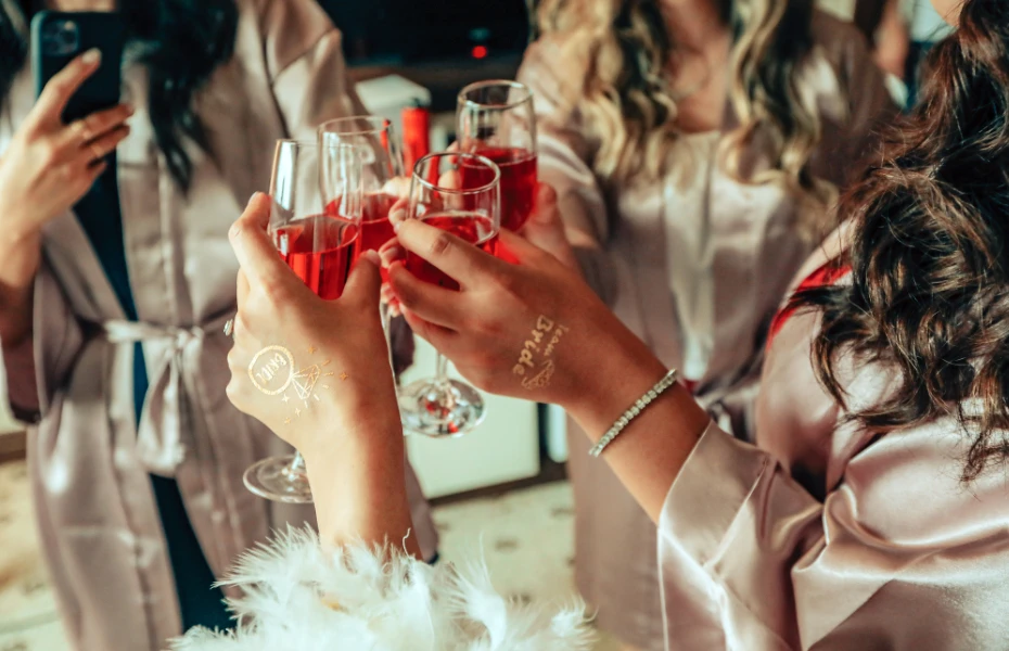 Freunde stoßen mit Gläsern voller roséfarbener Getränke an, während sie sich in eleganten Morgenmänteln vorbereiten.