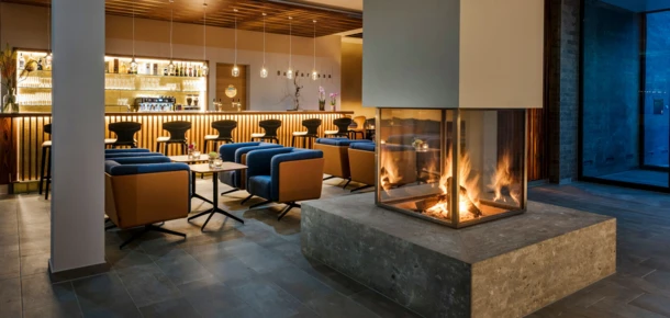 Modern lounge with a cozy fireplace at Hotel Klosterhof. Comfortable seating and a well-stocked bar create a welcoming atmosphere.