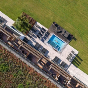 Eine Luftaufnahme des Hotel Klosterhof mit einem Pool und Liegen auf einer gepflegten Rasenfläche in Bayerisch Gmain.