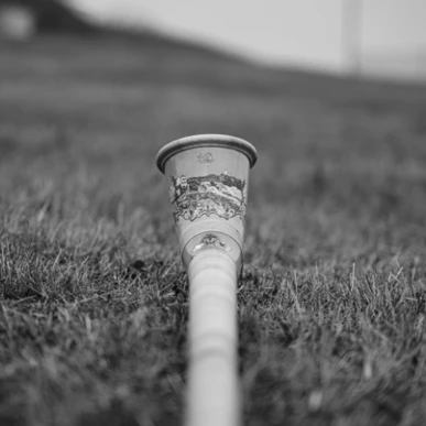 Ein Blick auf einen dekorativen Becher, der im Gras liegt, vor einer sanften, verschwommenen Landschaft. Ideal für entspannende Momente im Hotel Klosterhof.